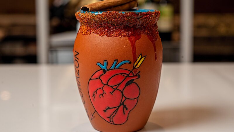 Close up view of a cocktail in a ceramic cup with a heart painted on it